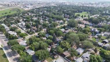 Arka planda evler ve ağaçlar olan şehir caddesi. Evler küçük ve cadde ağaçlarla kaplı.