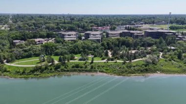 İçinden nehir akan bir şehir. Nehir yeşil ve binalar yüksektir. Gökyüzü mavi ve güneş parlıyor.