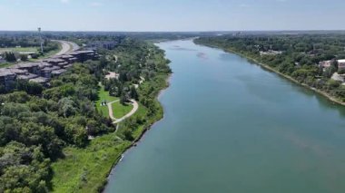 Nehir evleri ve parkı olan bir kasabadan geçiyor. Su yeşil ve sakindir. Gökyüzü açık ve parlak