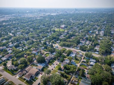 Şehir manzarası yukarıdan birçok ev ve ağaçla dolu. Evler çoğunlukla beyaz ve ağaçlar yeşil.