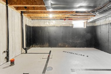 Büyük, boş, siyah duvarı ve beyaz zemini olan bir oda. Oda tamamlanmamış ve endüstriyel bir havası var.