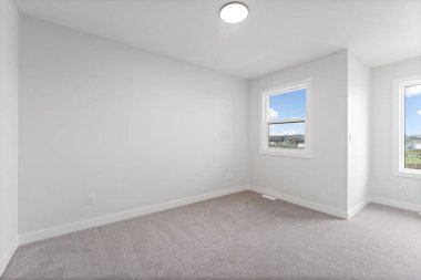 Penceresi ve lambası olan beyaz bir oda. Oda boş ve minimalist bir görünüşü var.