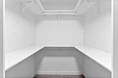 Beyaz duvarları ve rafları olan küçük, boş bir dolap. Dolap neredeyse çıplak, sadece birkaç şey görünüyor. Mekan minimalist ve dağınık, sakinlik ve sadelik hissi veriyor.