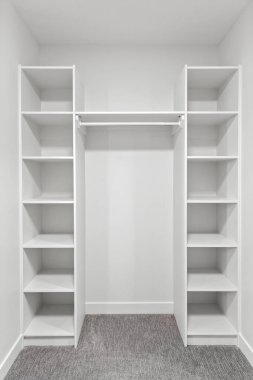 Beyaz rafları ve beyaz kapısı olan çok temiz ve düzenli bir dolap. Dolap boş ve minimalist bir havası var.