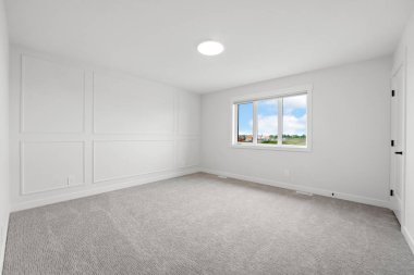 Büyük, penceresi ve aydınlatma armatürü olan boş bir oda. Oda beyaz ve temiz, minimalist bir görünüme sahip.