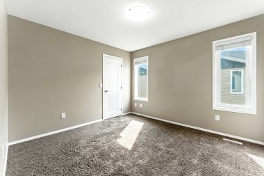 Room with a white door and a window. The room is empty. There is a carpet on the floor