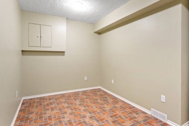 Small room with a tan wall and a brick floor. The room is empty and has no furniture