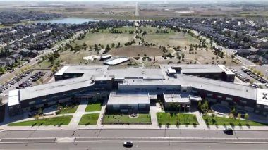 4K aerial view of Stonebridge in Saskatoon, showing modern homes, parks, and busy retail areas in this southside community.