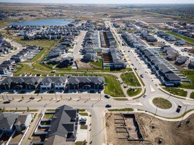 Drone aerial of Brighton, Saskatoon, featuring modern homes, wetlands, and suburban streets.