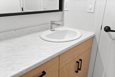 Bathroom sink with a mirror above it. The sink is white and the counter is marble. The bathroom is clean and well-maintained