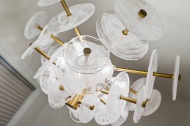 Üzerinde bir sürü cam top olan bir avize. Avize berrak camdan yapılmıştır ve altın bir çerçevesi vardır. Avize tavandan sarkıyor ve görüntünün odak noktası.