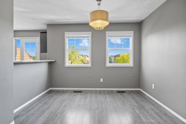 Large, empty room with a white wall and a grey floor. The room has a large window with a view of the outside