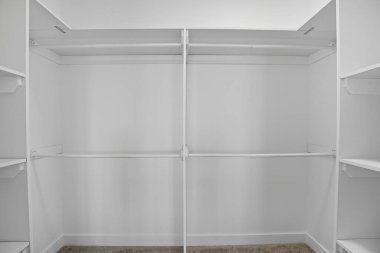 Dolaptaki boş yürüyüş çok ferah ve temiz. Beyaz duvarlar ve raflar odayı aydınlık ve havadar hissettiriyor.