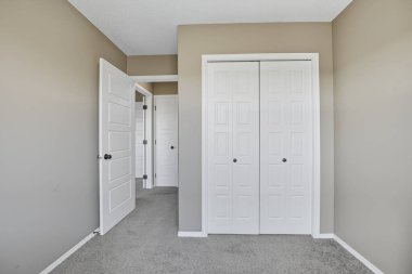 Beyaz kapısı ve beyaz dolabı olan beyaz bir oda. Oda boş ve minimalist bir görünüşü var.