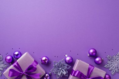 Noel arifesi kavramı. Leylak hediye kutularının üst görünümü kurdele yayları, çiçek süslemeleri, mor mücevherler ve boş mor arkaplan üzerine konfetiler.