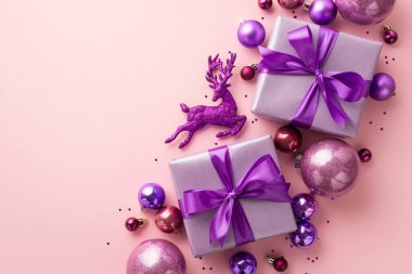 Noel konsepti. Leylak hediye kutularının üst görüntüsü kurdele yayları pembe menekşe takılar ren geyiği süsü ve tenha pastel pembe arka planda boş alan ile konfeti.
