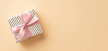 Noel arifesi kavramı. Üstteki panoramik fotoğraf şık hediye kutusu pembe kurdele ile izole edilmiş açık bej arkaplan ve kopyalanmış alan