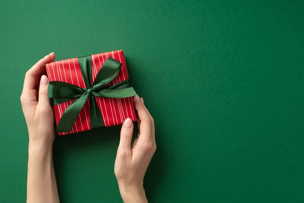 新年的概念 第一人称顶部照片女孩的手拿着红色礼品盒带蝴蝶结孤立的绿色背景与复制空间 — 图库照片
