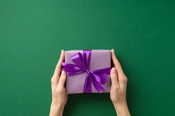 新年的概念 第一人称头像女用手送给紫色礼品盒的照片 礼品盒上有紫色丝带 背景为孤立的绿色 — 图库照片