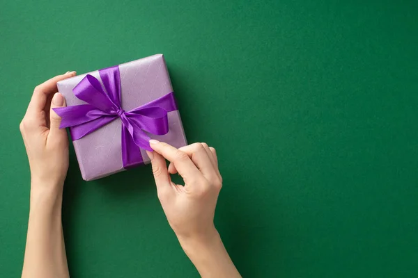 新年的概念 第一人称头像照片年轻女子的手打开包装紫带蝴蝶结紫丁香礼盒在孤立的绿色背景与空旷的空间 — 图库照片