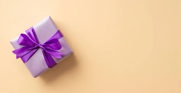 新年的概念 带紫带蝴蝶结的时尚紫丁香礼品盒在孤立的彩色米色背景上的全景全景照片集 — 图库照片