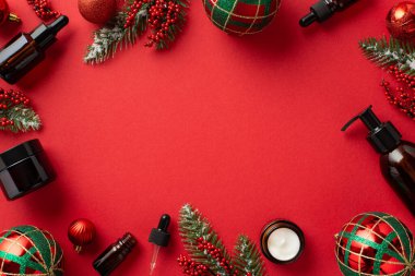 Kış mevsimi cilt bakımı. Noel dekoru kırmızı ve yeşil takılar kehribar cam şişeler ökse otu üzümleri ve köknar dalları izole edilmiş kırmızı arkaplan ve ortasında kopyalanmış boşluk