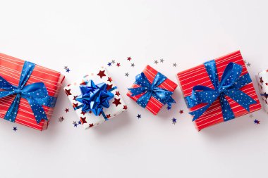 ABD Bağımsızlık Günü konsepti. Ulusal bayrak renklerinde hediye kutularının ve izole edilmiş beyaz arka planda yıldız şekilli konfetilerin en üstteki görüntüsü