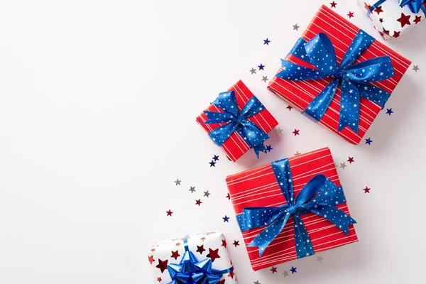USA Independence Day concept. Top view photo of present boxes with ribbon bows and star shaped confetti on isolated white background with empty space