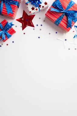 ABD Bağımsızlık Günü konsepti. Ulusal bayrak renklerinde mevcut kutuların dikey üst görünümü yıldız çelengi ve izole edilmiş beyaz arka planda parlayan konfeti