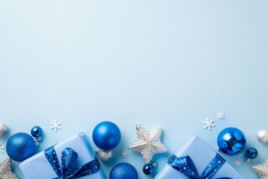 Noel Günü konsepti. Mavi ve gümüş mücevherlerin en üstteki fotoğrafı parıldayan yıldız süslemeleri şık mevcut kutular ve izole edilmiş açık mavi arkaplan üzerinde kar tanesi şekilli konfeti boş alan