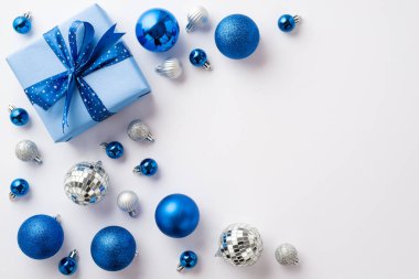 Noel konsepti. Mavi beyaz mücevher disko topları ve kopyalanmış beyaz arka planda kurdele ile büyük hediye kutusu.