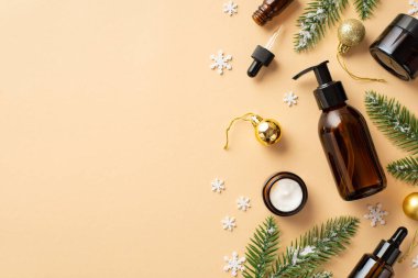 Kış cilt bakım konsepti. Etiketsiz kehribar pompa şişesinin üst görüntüsü. Krema şişeleri, altın mücevherler. Karda köknar dalları ve izole edilmiş bej arka planda kar taneleri.