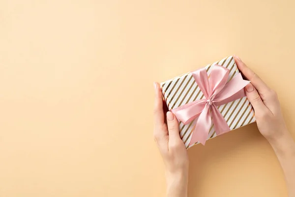 新年的概念 第一人称头像女用手送给礼物盒的照片 盒子上有粉色丝带蝴蝶结 背景为孤立的米黄色 — 图库照片