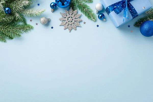 stock image New Year celebration concept. Top view photo of giftbox with bow blue and white baubles snowflake ornament pine branches in snow and confetti on isolated pastel blue background with copyspace