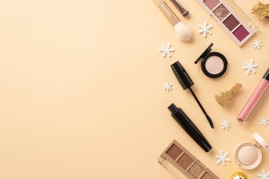 Kış tatili alışverişi. Dekoratif kozmetik, pembe dudak parlatıcısı, maskara göz falı paletleri altın süsler ve izole edilmiş bej arka planda kar taneleri.