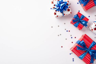 4 Temmuz kutlama konsepti. Kurdele yay ve yıldız şekilli konfetilerin boş arkaplan ile izole edilmiş beyaz arkaplan üzerindeki mevcut kutuların üst görünüm fotoğrafı