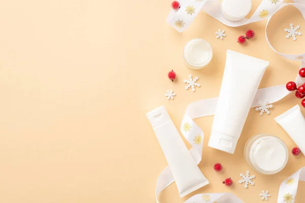 Winter skincare products concept. Top view photo of white tubes jars curly ribbon mistletoe berries and snowflakes on isolated beige background with copyspace