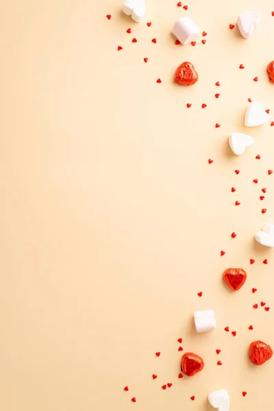 stock image Valentine's Day concept. Top view vertical photo of heart shaped candies and confetti on isolated beige background with copyspace