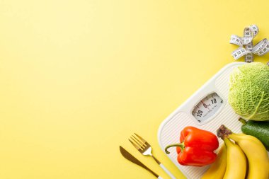 Diyet konsepti. Sebze ve meyve kabağı, lahana, çan biberi, muz biberi, mezura ve izole edilmiş pastel sarı arka planda boş alan ile pulların en üst görüntüsü.