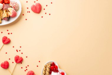 Sevgililer Günü konsepti. Kalp şeklindeki fincan tabakları, şekerli şekerler lolipoplar ve izole edilmiş bej arkaplanlı konfetiler.