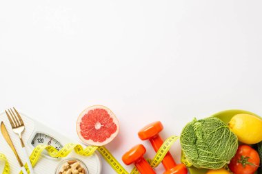 Kilo verme konsepti. Sebze, greyfurt, lahana, limon, fındık, çatal bıçak, dambıl ve kopyalanmış beyaz arka planda mezura.