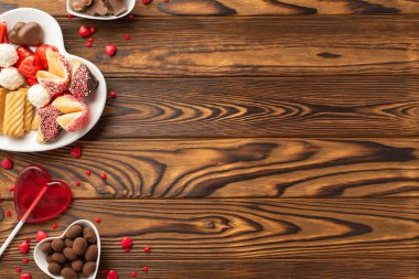 Sevgililer Günü kutlaması konsepti. Kalp şeklindeki tabakların en üst görüntüsü. Çikolata jöleli şekerler. Lolipop ve hamur işi.