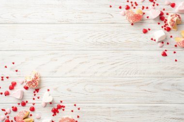 Sevgililer Günü konsepti. Telif alanı olan beyaz ahşap masa arkaplanındaki kalp şeklindeki kurabiye ve şekerlemelerin üst görünüm fotoğrafı