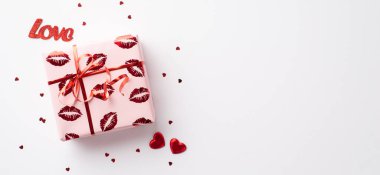 Sevgililer Günü konsepti. Üst panoramik görünüm fotoğrafı ambalaj kağıdında, öpücük dudakları desenli kırmızı kalpler izole edilmiş beyaz arkaplanda aşk ve konfeti.