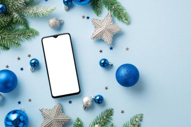 Noel Günü konsepti. Akıllı telefon mavi ve beyaz takılar gümüş yıldız süslemeleri beyaz don içinde çam dalları ve izole edilmiş pastel mavi arka plan üzerinde parlak konfeti