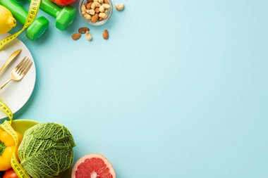 Uygun diyet konsepti. Çatal bıçak takımının en üst görüntüsü lahana biberi greyfurt dambılları ve bant ölçüsü izole edilmiş pastel mavi arka planda boş alan