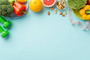 Zayıflatıcı konsept. Meyve ve sebzeli tabaklar, lahana, karabiber, greyfurt, fındık dambılı ve izole edilmiş pastel mavi arka planda bant ölçüsü.