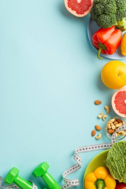 Kilo verme konsepti. Üst görünümde meyve ve sebzeli tabaklar, lahana, karabiber, greyfurt, fındık halterli halterler, izole edilmiş pastel mavi arkaplan üzerine bant ölçüsü.