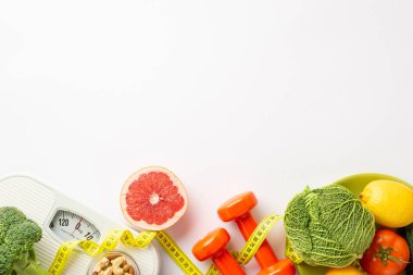 Kilo verme konsepti. Greyfurt, lahana, karnabahar, limon, fındık, halterler ve izole edilmiş beyaz arka planda mezura.