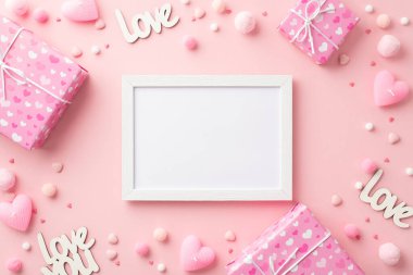 Sevgililer Günü konsepti. Fotoğraf çerçevesi hediye kutularının en üstteki fotoğrafı kalp şeklinde mumlar aşk serpintileri ve pofuduk püsküllü ponponlar izole edilmiş pembe arka planda ortada kopyalanmış alan